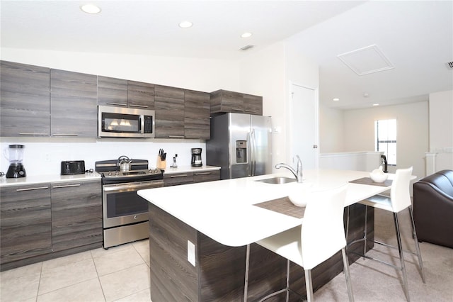 kitchen with sink, appliances with stainless steel finishes, an island with sink, and a breakfast bar area