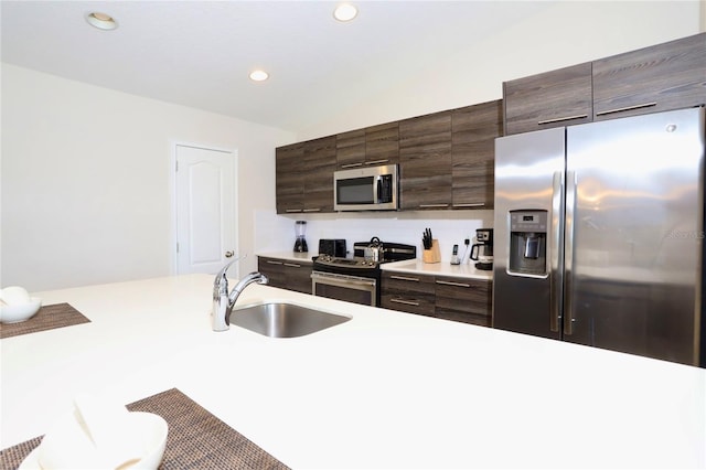 kitchen featuring dark brown cabinetry, sink, appliances with stainless steel finishes, and a kitchen bar