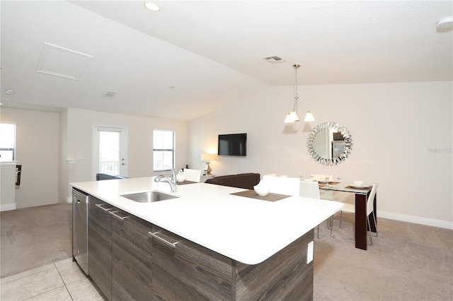 kitchen with sink, vaulted ceiling, light tile floors, and a center island with sink