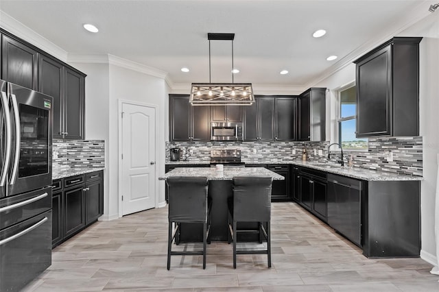 kitchen featuring a kitchen island, appliances with stainless steel finishes, decorative light fixtures, sink, and light stone counters