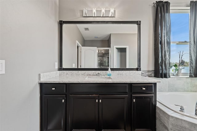 bathroom featuring vanity, plenty of natural light, and tiled bath