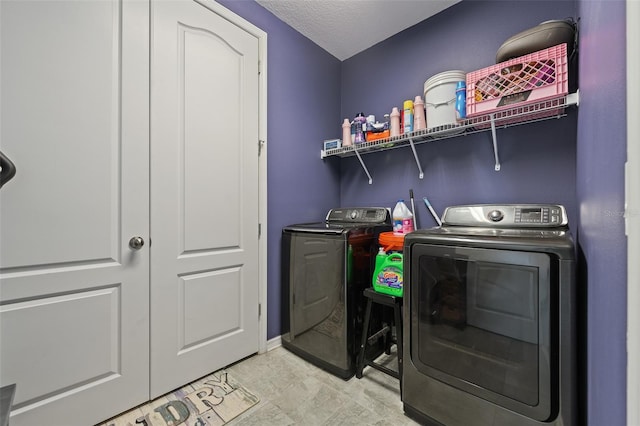 clothes washing area with washing machine and dryer and a textured ceiling