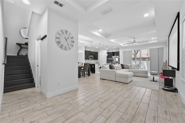 living room with ceiling fan and a raised ceiling