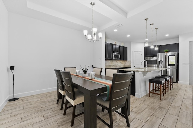 dining room with sink, light wood-type flooring, and an inviting chandelier