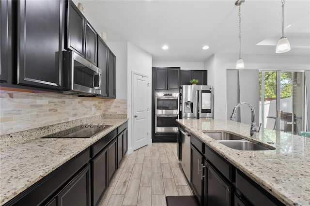 kitchen featuring decorative light fixtures, stainless steel appliances, tasteful backsplash, light stone countertops, and sink