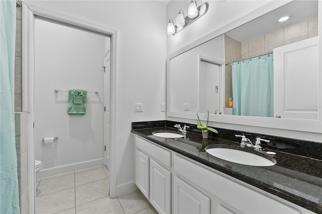 bathroom featuring vanity with extensive cabinet space, double sink, toilet, and tile floors