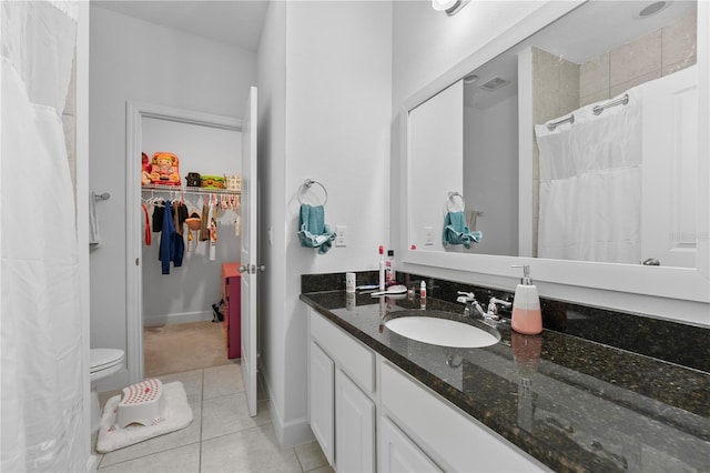 bathroom featuring vanity with extensive cabinet space, toilet, and tile floors