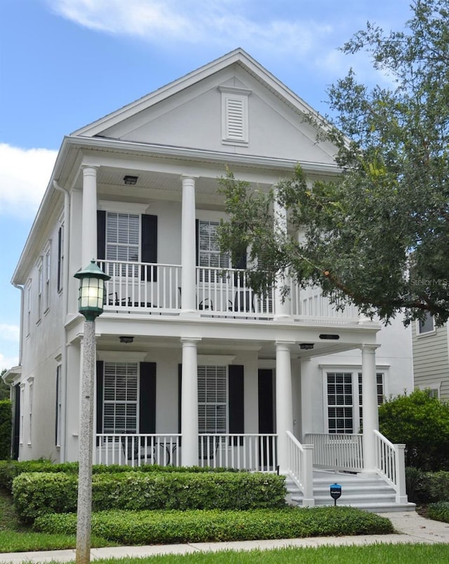 greek revival inspired property with a balcony and covered porch