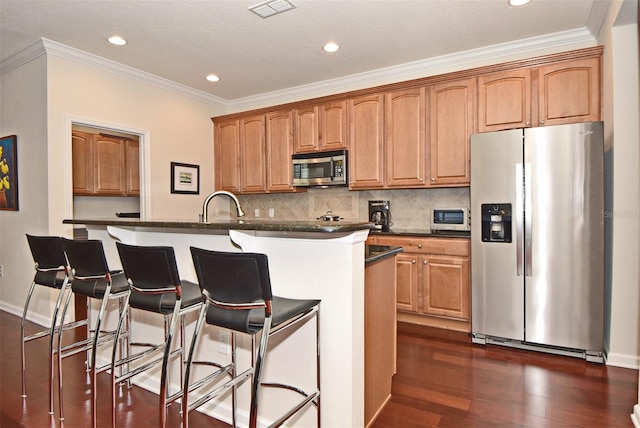 kitchen featuring stainless steel appliances, tasteful backsplash, dark wood-type flooring, a kitchen island with sink, and ornamental molding