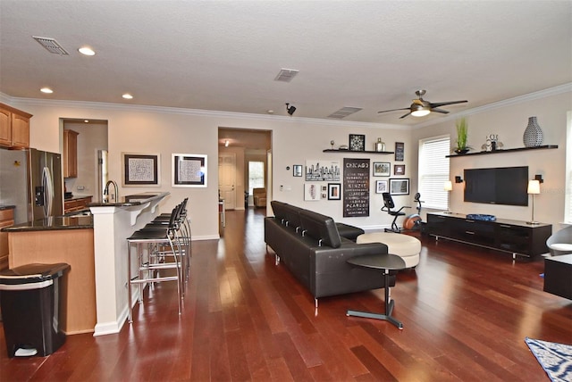 living room with ceiling fan, crown molding, and dark wood-type flooring