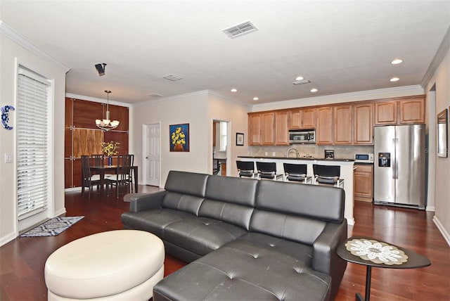 living room with crown molding, a chandelier, and dark wood-type flooring