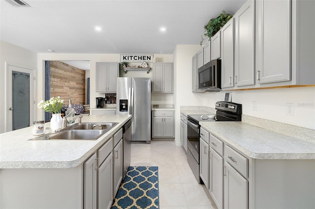 kitchen featuring light tile flooring, gray cabinets, sink, a kitchen island with sink, and appliances with stainless steel finishes