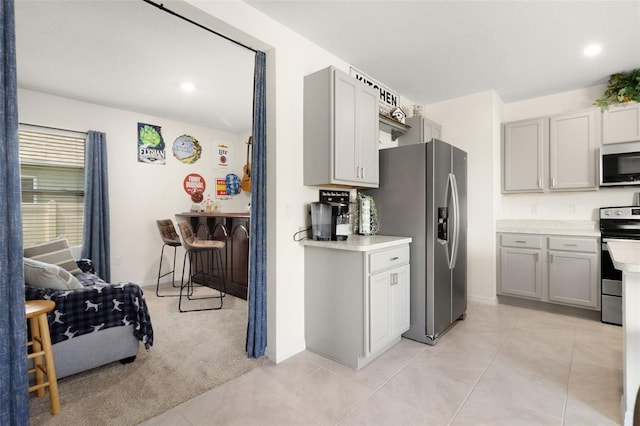 kitchen with gray cabinetry, light tile floors, and stainless steel appliances