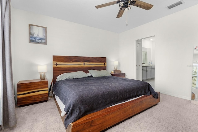 bedroom with ceiling fan, ensuite bathroom, and light carpet