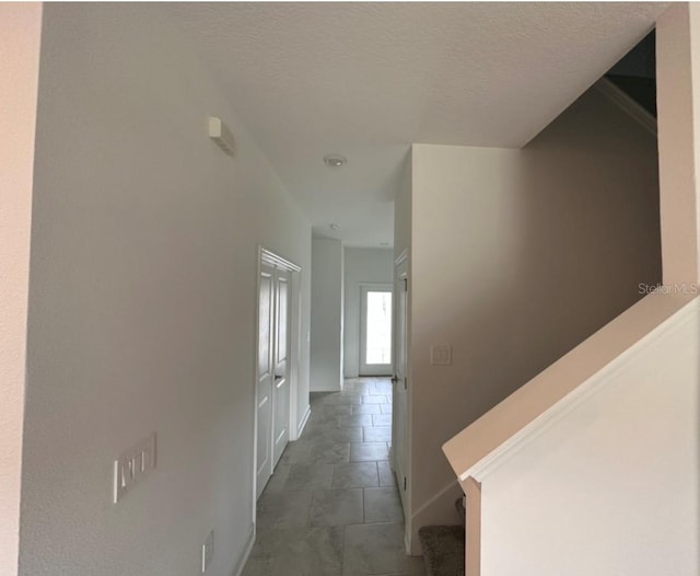 corridor featuring dark tile floors and a textured ceiling