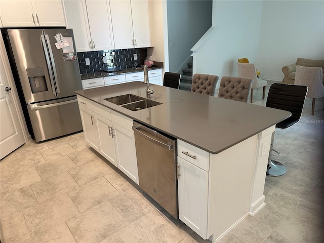 kitchen with backsplash, sink, stainless steel appliances, and a center island with sink