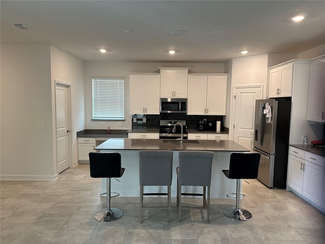 kitchen with a kitchen island with sink, a kitchen bar, stainless steel appliances, and sink