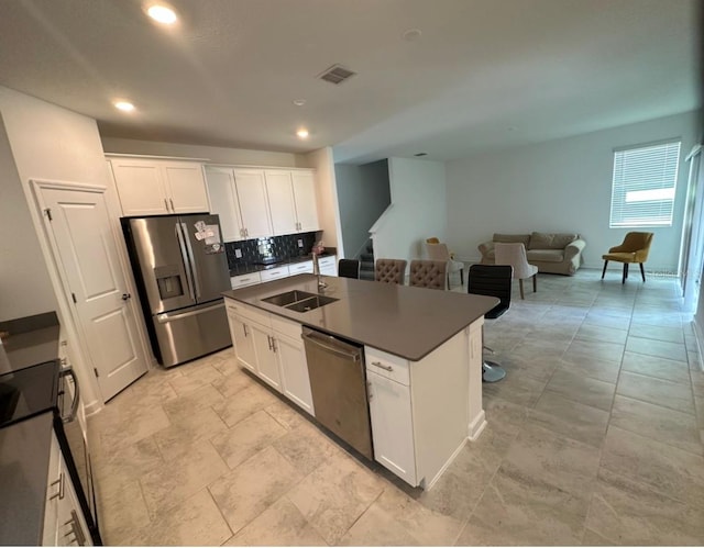 kitchen featuring a kitchen island with sink, light tile flooring, white cabinetry, backsplash, and appliances with stainless steel finishes