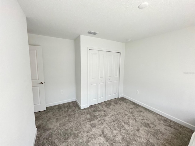 unfurnished bedroom featuring a closet and dark colored carpet