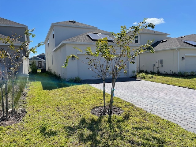 view of front of property featuring solar panels, a garage, and a front yard