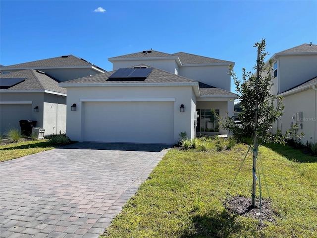 view of front of property featuring a front yard, solar panels, and a garage