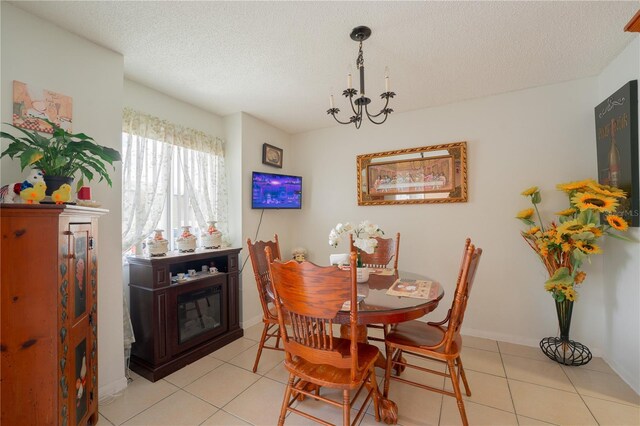 dining space with a textured ceiling, an inviting chandelier, and light tile patterned floors