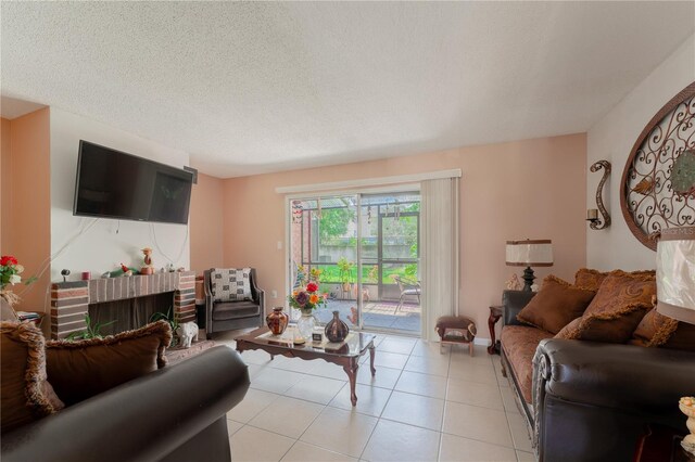 tiled living room featuring a textured ceiling and a brick fireplace