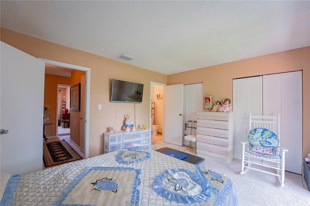 bedroom featuring a textured ceiling, two closets, and carpet floors