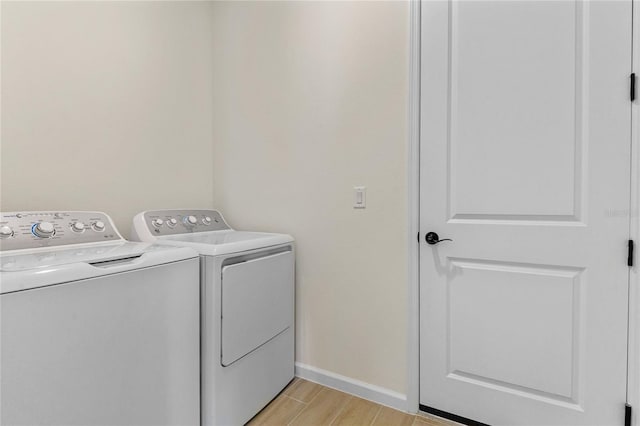 laundry area with light hardwood / wood-style floors and washing machine and dryer