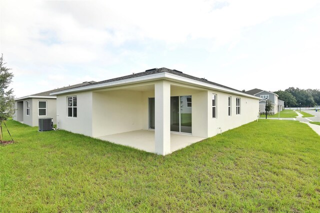 back of property with a patio, central air condition unit, and a yard