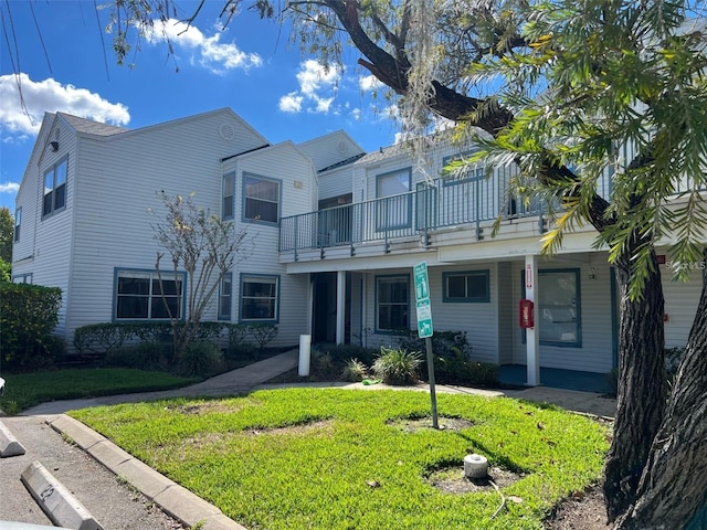 view of property featuring a front lawn and a balcony