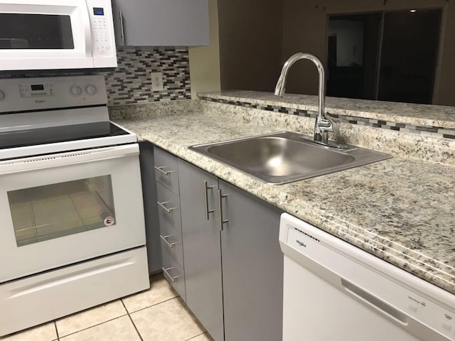 kitchen featuring gray cabinetry, tasteful backsplash, sink, white appliances, and light tile floors