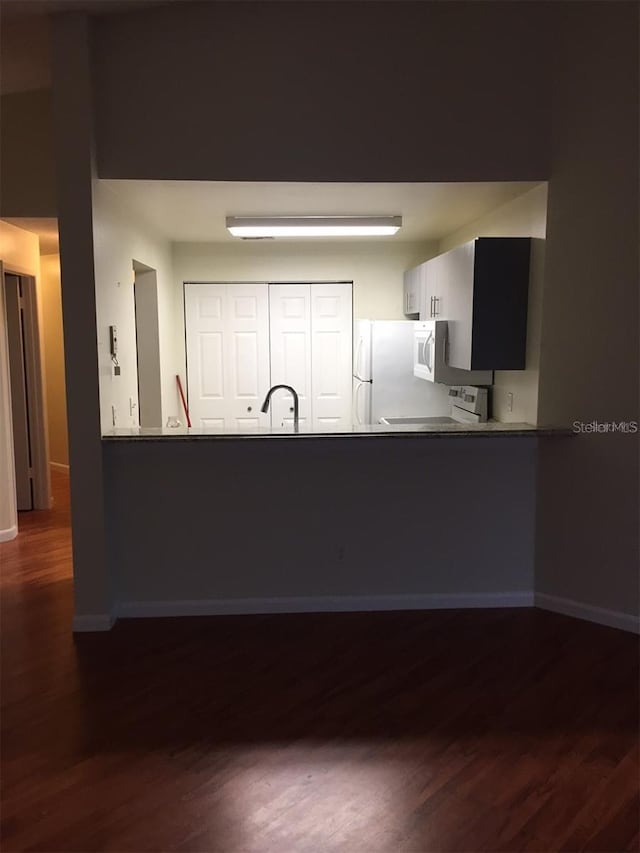 kitchen featuring white appliances, sink, dark wood-type flooring, and white cabinetry