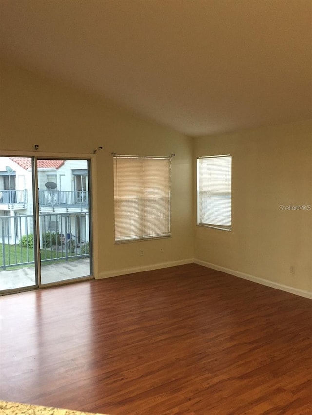 spare room with dark wood-type flooring and vaulted ceiling