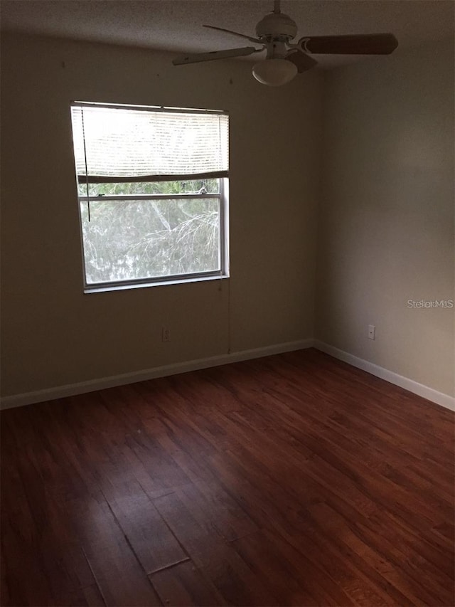 spare room with dark wood-type flooring and ceiling fan