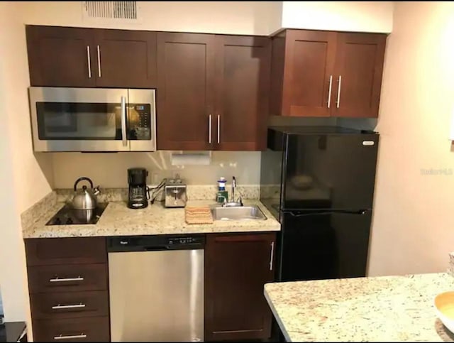 3100 Parkway Blvd Unit 717, Kissimmee, FL 34747 - kitchen featuring black appliances, dark brown cabinets, light stone counters, and a sink