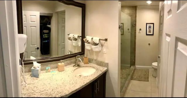 bathroom featuring a shower with door, vanity, toilet, and tile patterned flooring