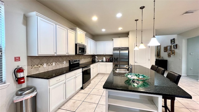 kitchen featuring a center island with sink, sink, decorative backsplash, appliances with stainless steel finishes, and white cabinetry