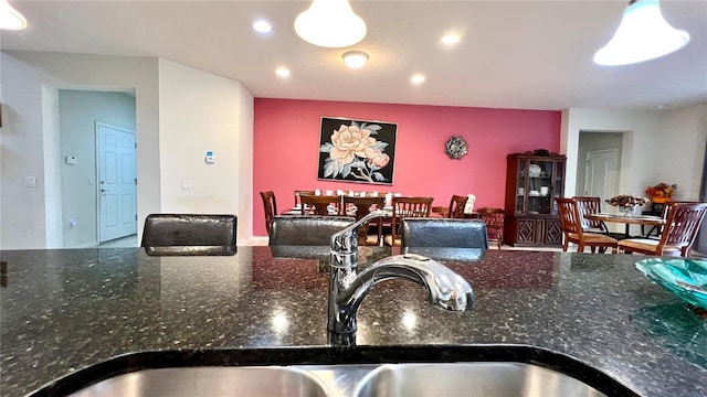 kitchen featuring hanging light fixtures, dark stone countertops, and sink