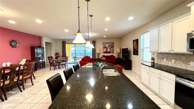 kitchen featuring decorative backsplash, dark stone counters, sink, pendant lighting, and white cabinetry