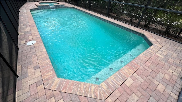 view of swimming pool featuring an in ground hot tub and glass enclosure