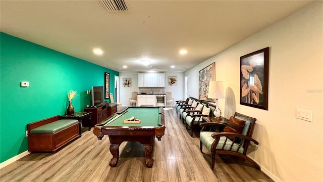 game room with light hardwood / wood-style floors, a textured ceiling, and billiards