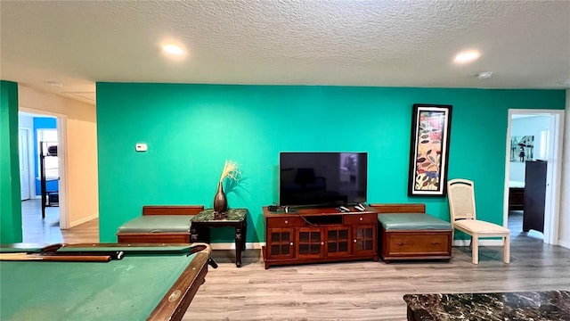 living room featuring a textured ceiling, pool table, and light hardwood / wood-style flooring