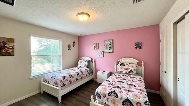 bedroom with a textured ceiling and dark wood-type flooring