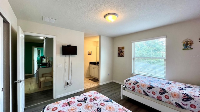 bedroom with dark hardwood / wood-style floors, a textured ceiling, connected bathroom, and a closet