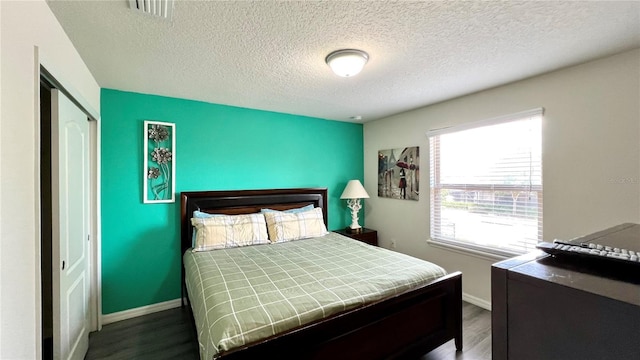 bedroom featuring a closet, dark wood-type flooring, and a textured ceiling