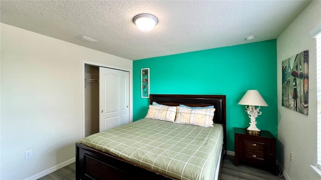 bedroom with a textured ceiling, dark wood-type flooring, and a closet