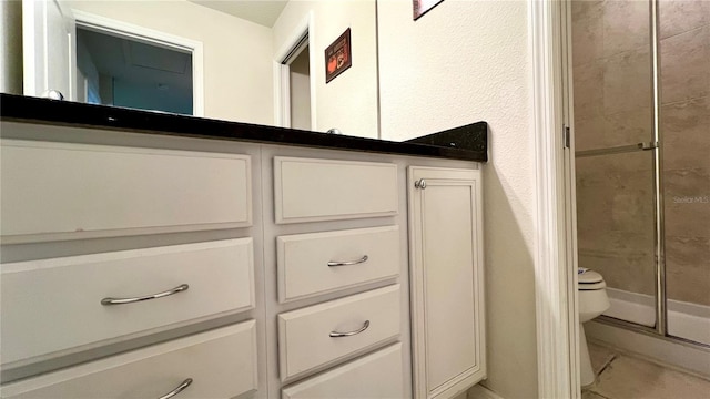 bathroom featuring tile patterned floors, vanity, an enclosed shower, and toilet