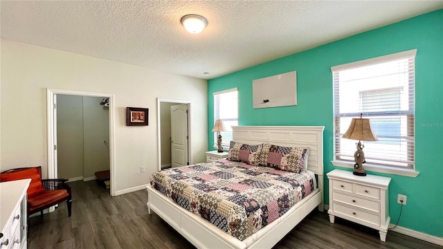 bedroom with a closet, a textured ceiling, dark hardwood / wood-style floors, and multiple windows