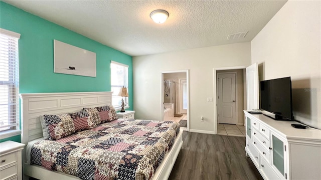 bedroom with a textured ceiling, multiple windows, ensuite bathroom, and dark hardwood / wood-style floors